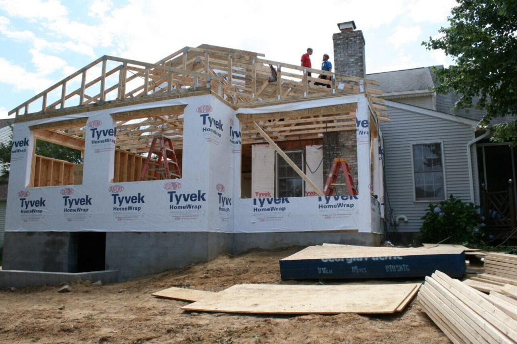 Addition being added onto a home with two workers standing on the roof