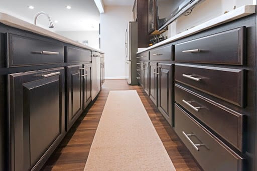 Kitchen walkway with dark cabinets