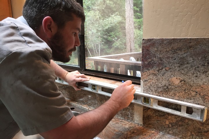 Skilled design-build contractor using a level to ensure precise countertop installation
