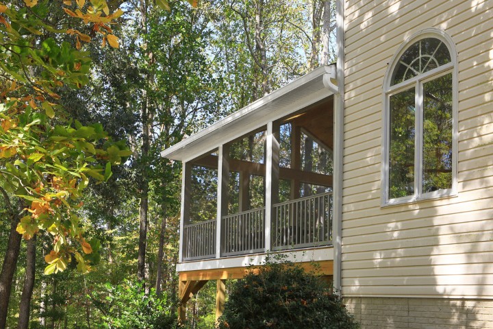 Elevated screened porch with wood railing home addition