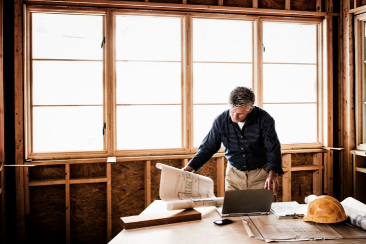 Home design-build contractor examining architectural plans for new addition