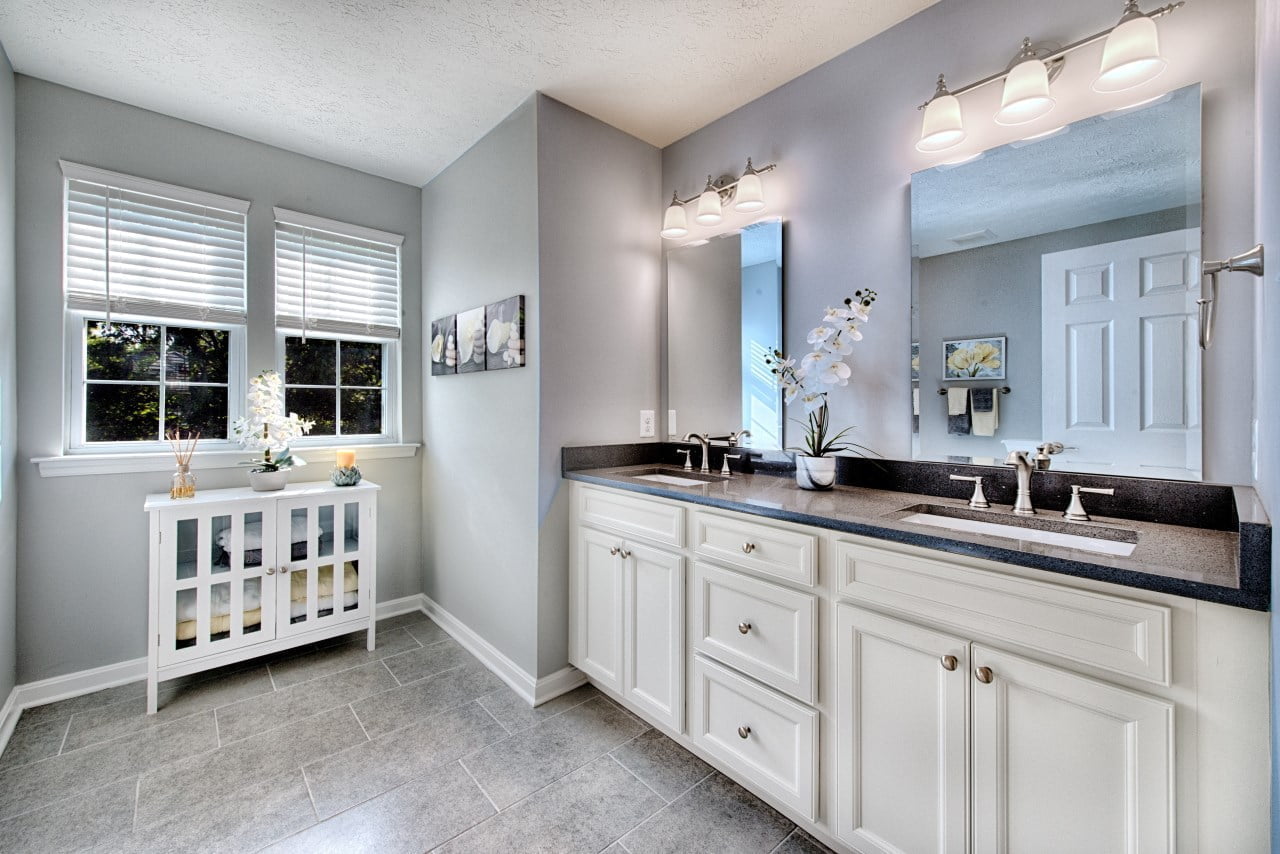 Stylish bathroom renovation with white cabinets and large mirrors