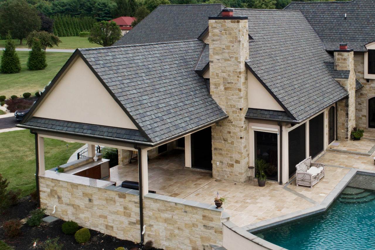 exterior home renovation featuring stone walls, pool, and covered patio