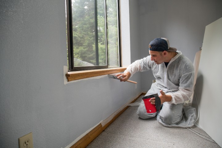 Home renovation contractor updating wall paint to refresh a residential interior