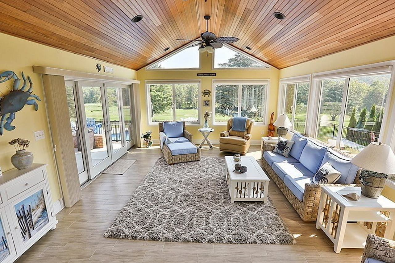 Airy sunroom remodel with coastal-inspired decor and soft blue seating