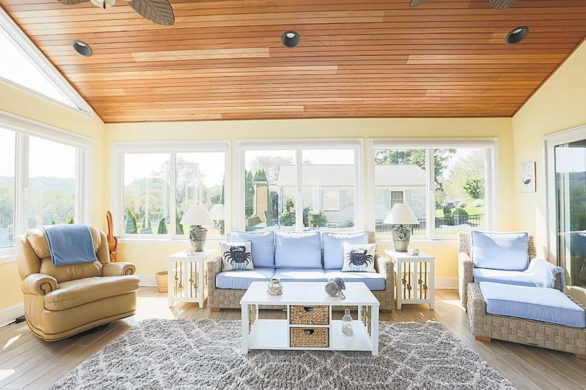 Harford County sunroom remodel showcasing wicker furniture and a warm wooden ceiling