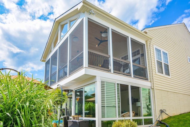 Two-story sunroom with glass walls and outdoor views designed by Maryland home addition contractors