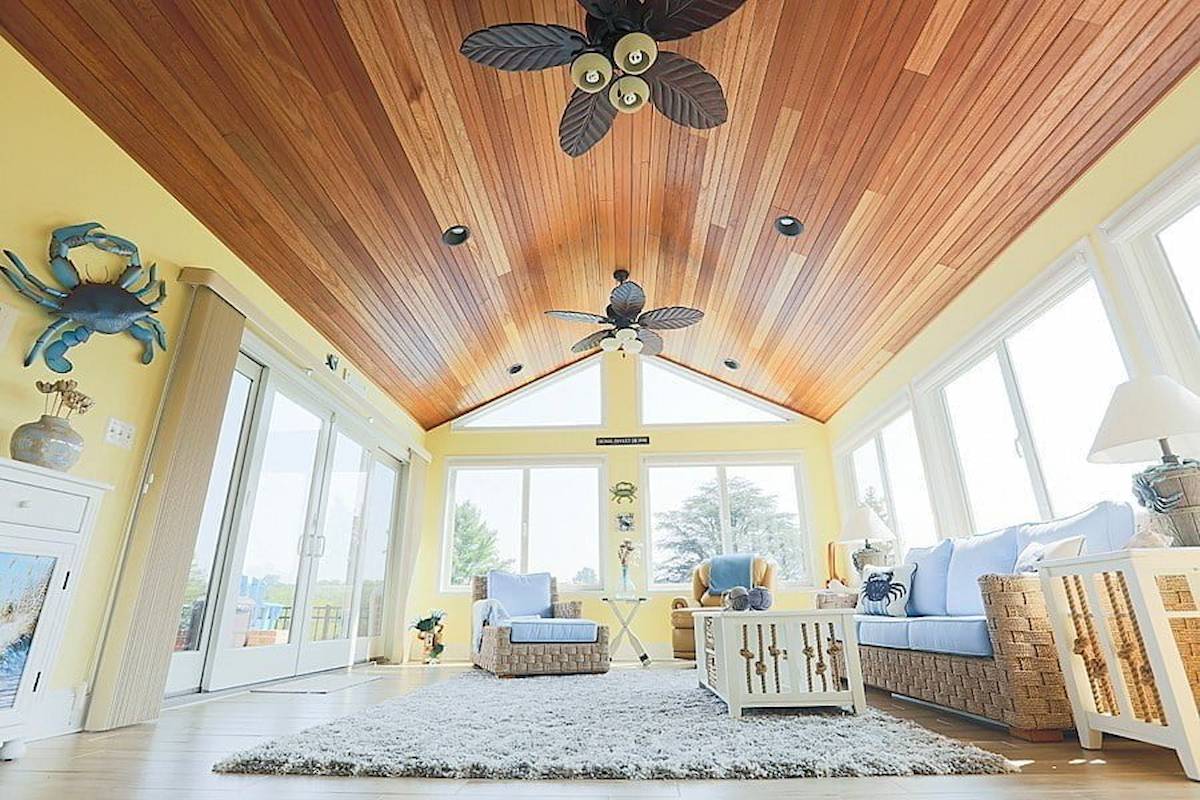 bright coastal-style sunroom created as a home addition in Maryland featuring wood ceilings and airy natural light